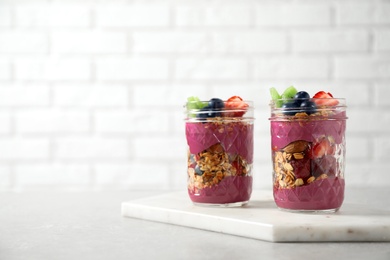 Tasty dessert with acai smoothie, granola and berries on marble table. Space for text