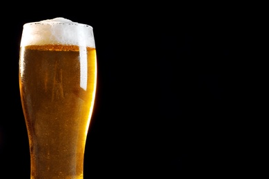 Photo of Cold tasty beer on black background, closeup. Space for text