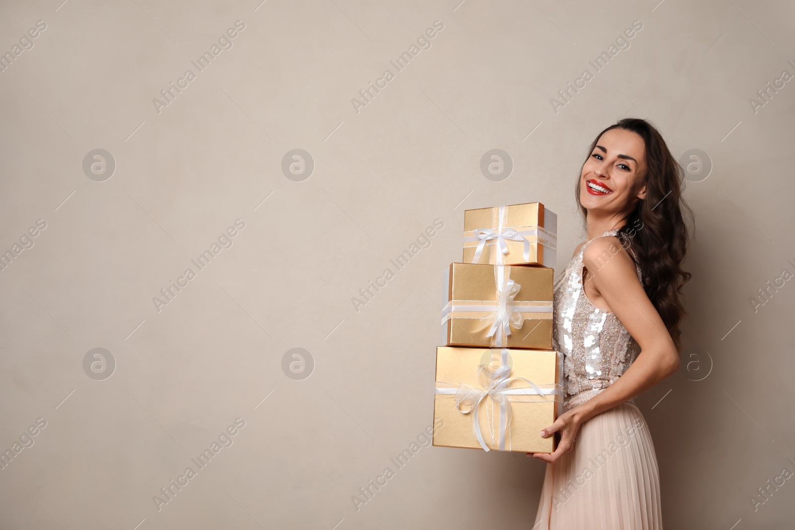 Photo of Beautiful woman with gift boxes on beige background, space for text. Christmas celebration