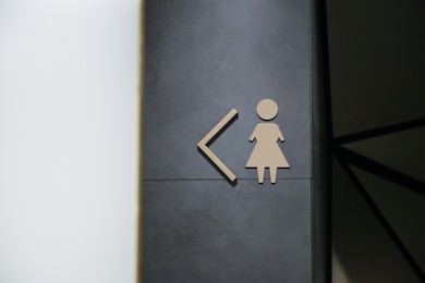 Image of Women's public toilet sign with arrow showing direction on wall