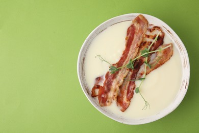 Photo of Delicious potato soup with bacon and microgreens on green background, top view. Space for text