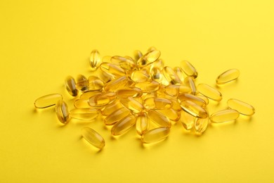 Pile of vitamin capsules on yellow background