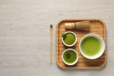 Fresh matcha tea, bamboo whisk, spoon and green powder on wooden table, flat lay. Space for text