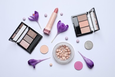 Flat lay composition with different makeup products and beautiful flowers on white background