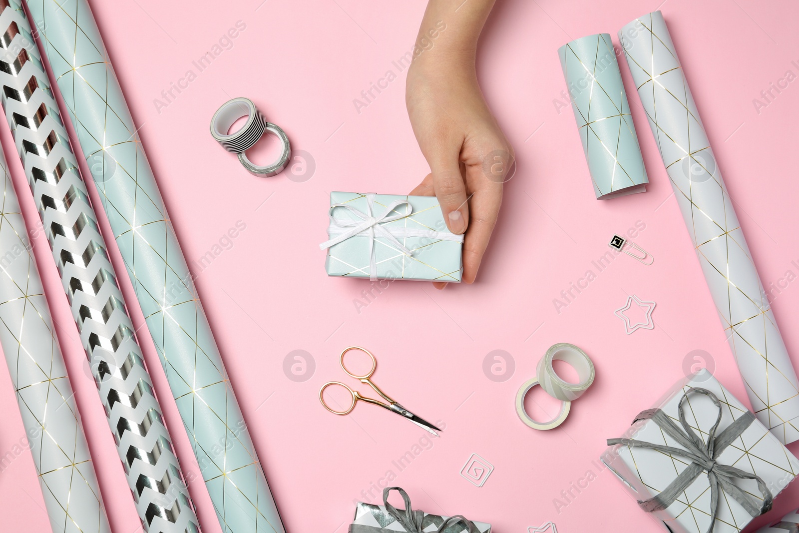 Photo of Woman with gift box and tools for decor on color background, view from above