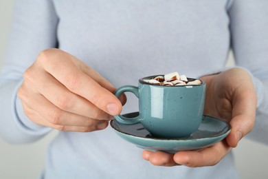 Photo of Woman holding cup of delicious hot chocolate with marshmallows and syrup, closeup