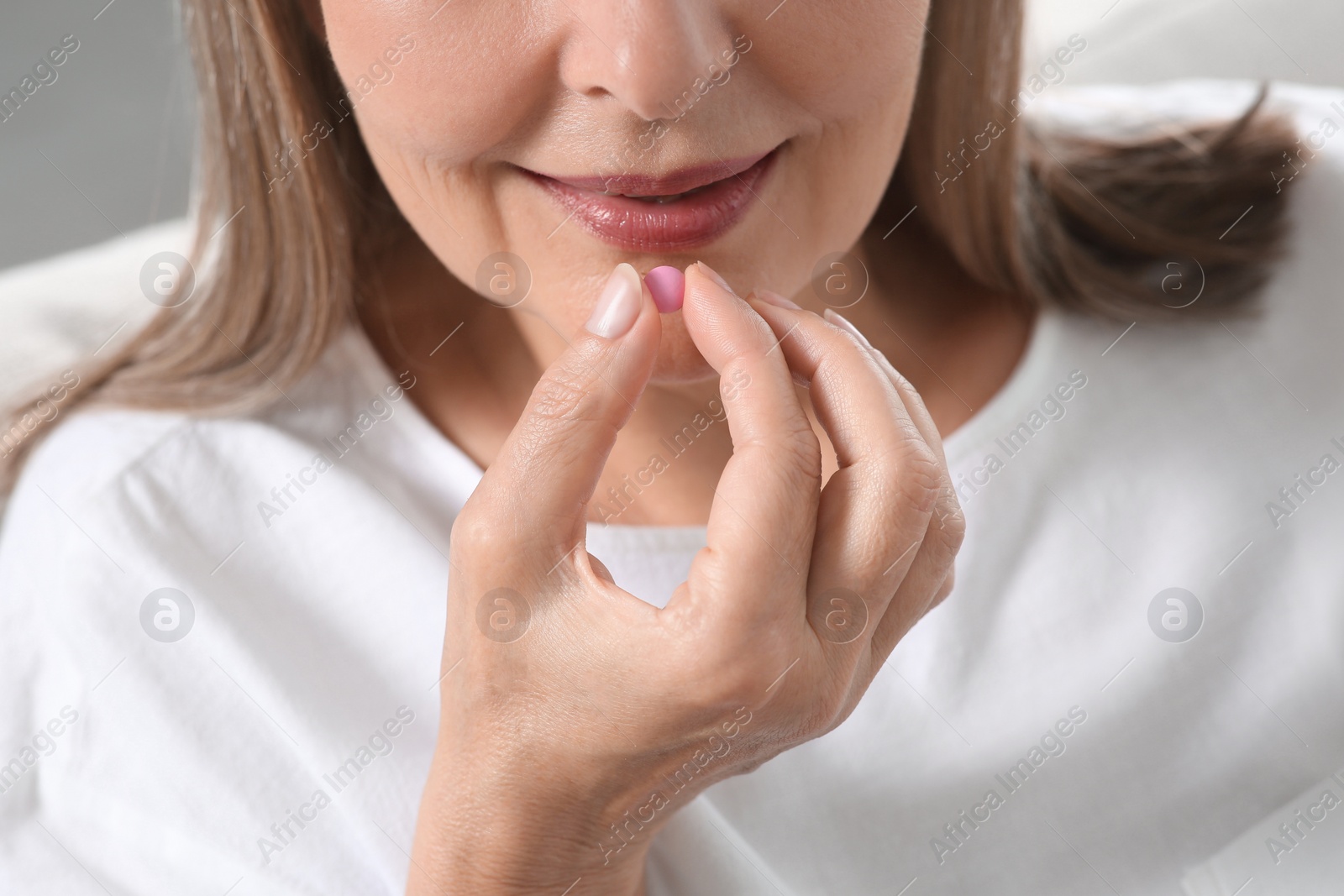 Photo of Senior woman taking pill indoors, closeup view