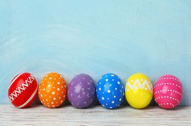 Decorated Easter eggs on table near color wall. Space for text