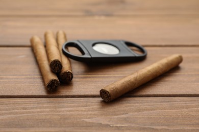 Photo of Cigars and guillotine cutter on wooden table