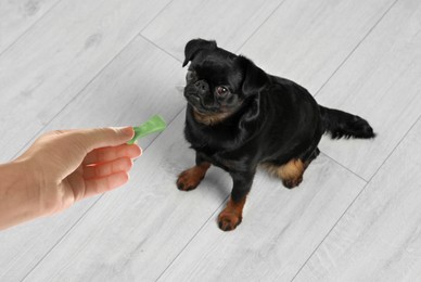 Image of Woman giving tasty bone shaped cookie to her dog indoors, above view
