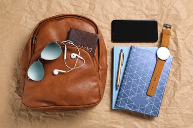 Photo of Stylish urban backpack and different items on parchment paper, flat lay