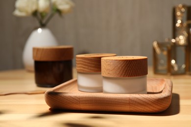 Jars of cream and tray on wooden table