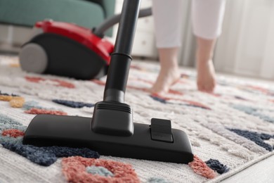 Woman cleaning carpet with vacuum cleaner at home, closeup. Space for text