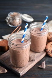 Photo of Jars with tasty chocolate milk on wooden table. Dairy drink
