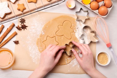 Photo of Woman making Christmas cookies with cutters at white wooden table, top view