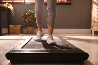 Photo of Sporty woman training on walking treadmill at home, closeup