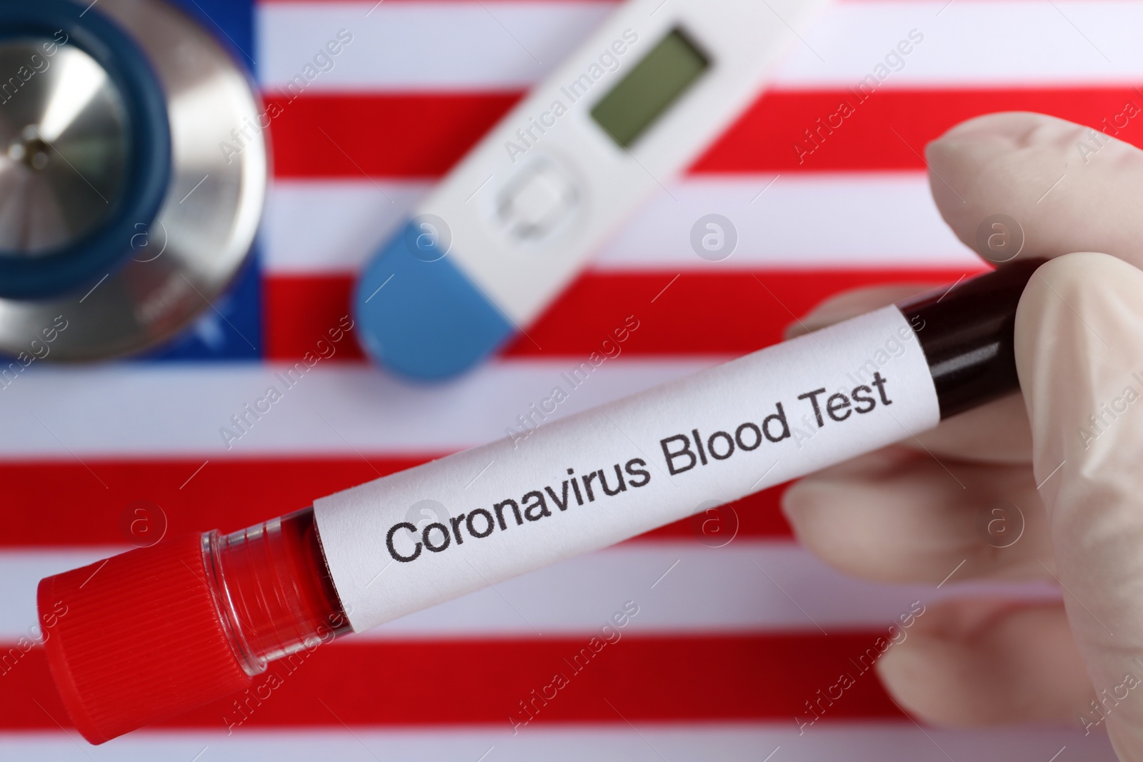 Photo of Scientist holding test tube with blood sample over American flag, closeup. Coronavirus pandemic in USA