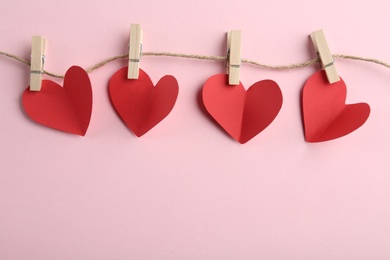 Photo of Red hearts, rope and clothespins on pink background, top view with space for text. St. Valentine's day