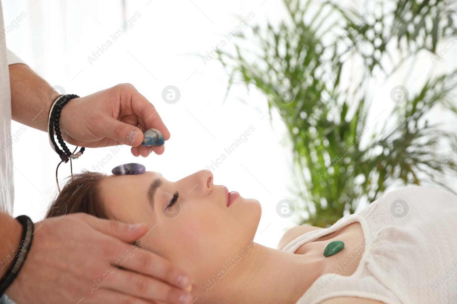 Photo of Young woman during crystal healing session in therapy room