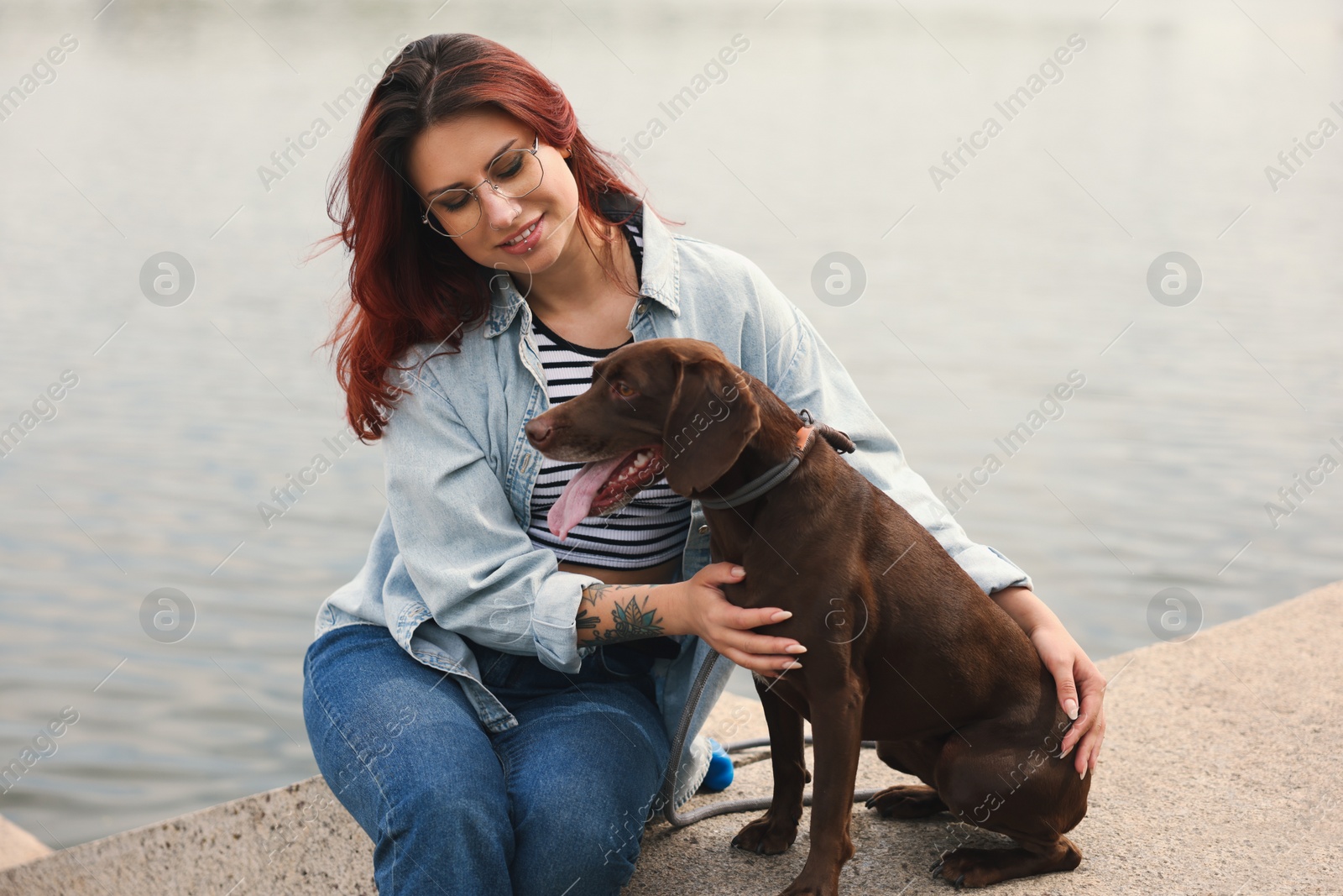 Photo of Woman with her cute German Shorthaired Pointer dog outdoors