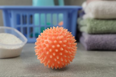 Photo of Orange dryer ball on grey marble table, closeup