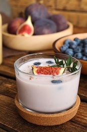 Photo of Delicious fig smoothie in glass on wooden table