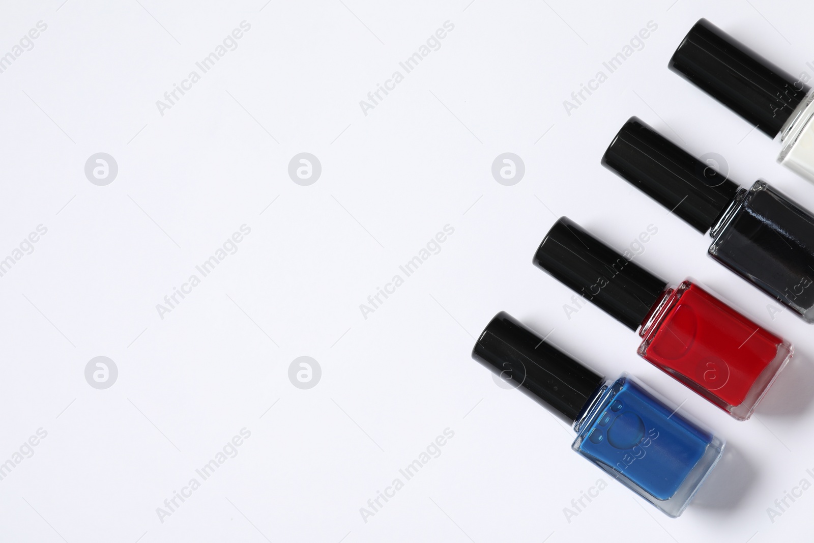 Photo of Nail polishes on white background, flat lay. Space for text