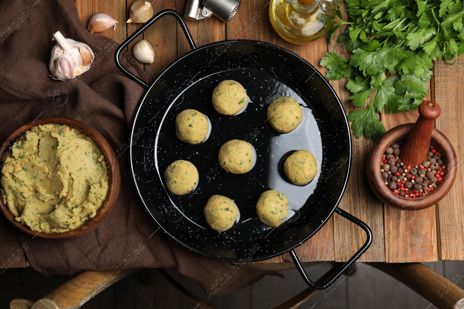 Photo of Raw falafel balls and ingredients on wooden table, flat lay