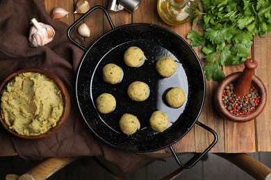 Photo of Raw falafel balls and ingredients on wooden table, flat lay