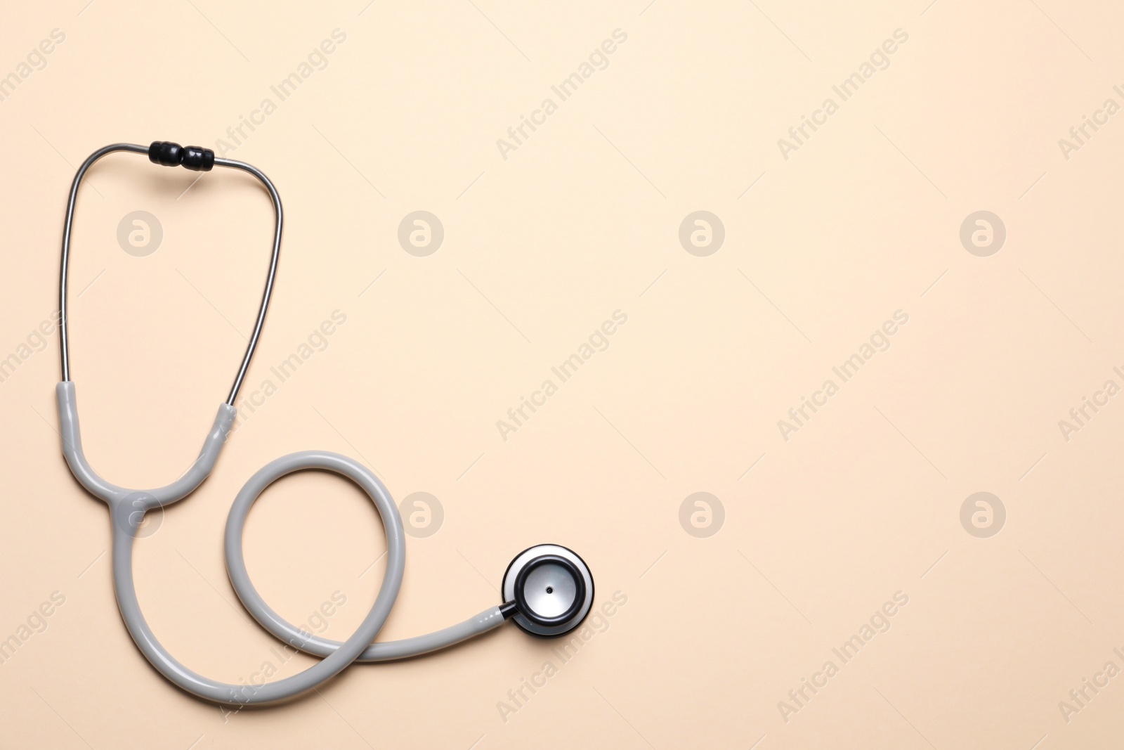 Photo of Stethoscope on beige background, top view. Space for text