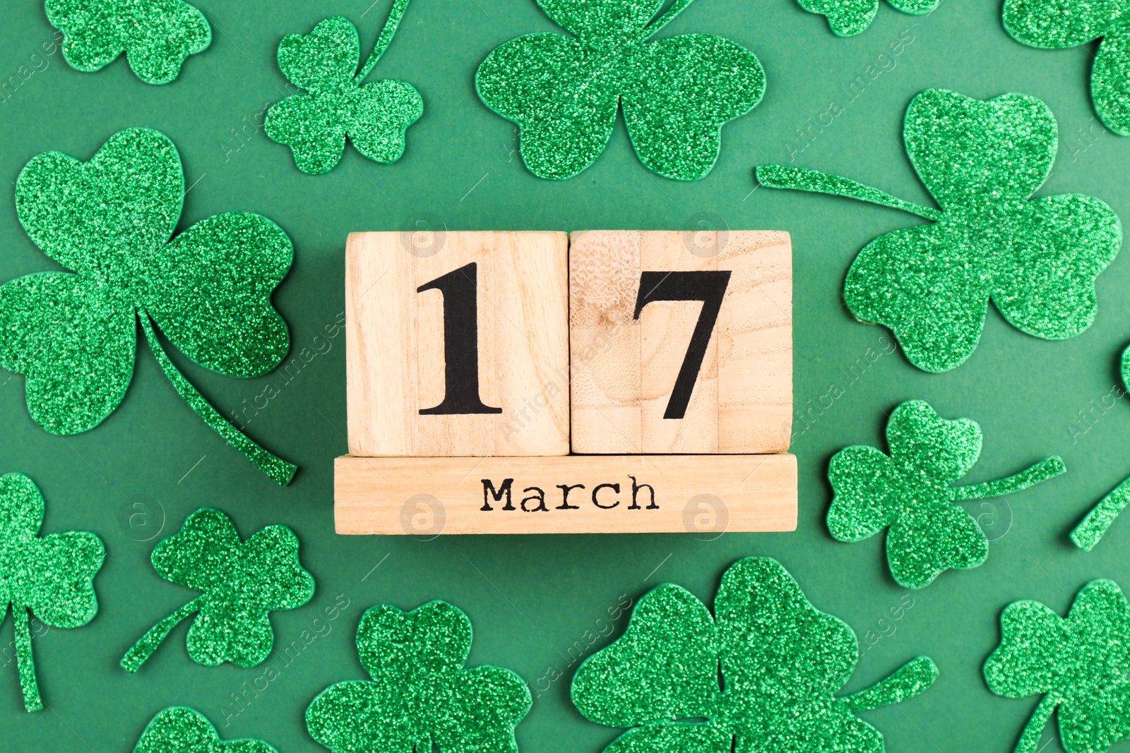 Photo of St. Patrick's day - 17th of March. Block calendar and decorative clover leaves on green background, flat lay