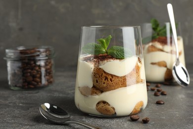 Photo of Delicious tiramisu with mint in glass on grey table