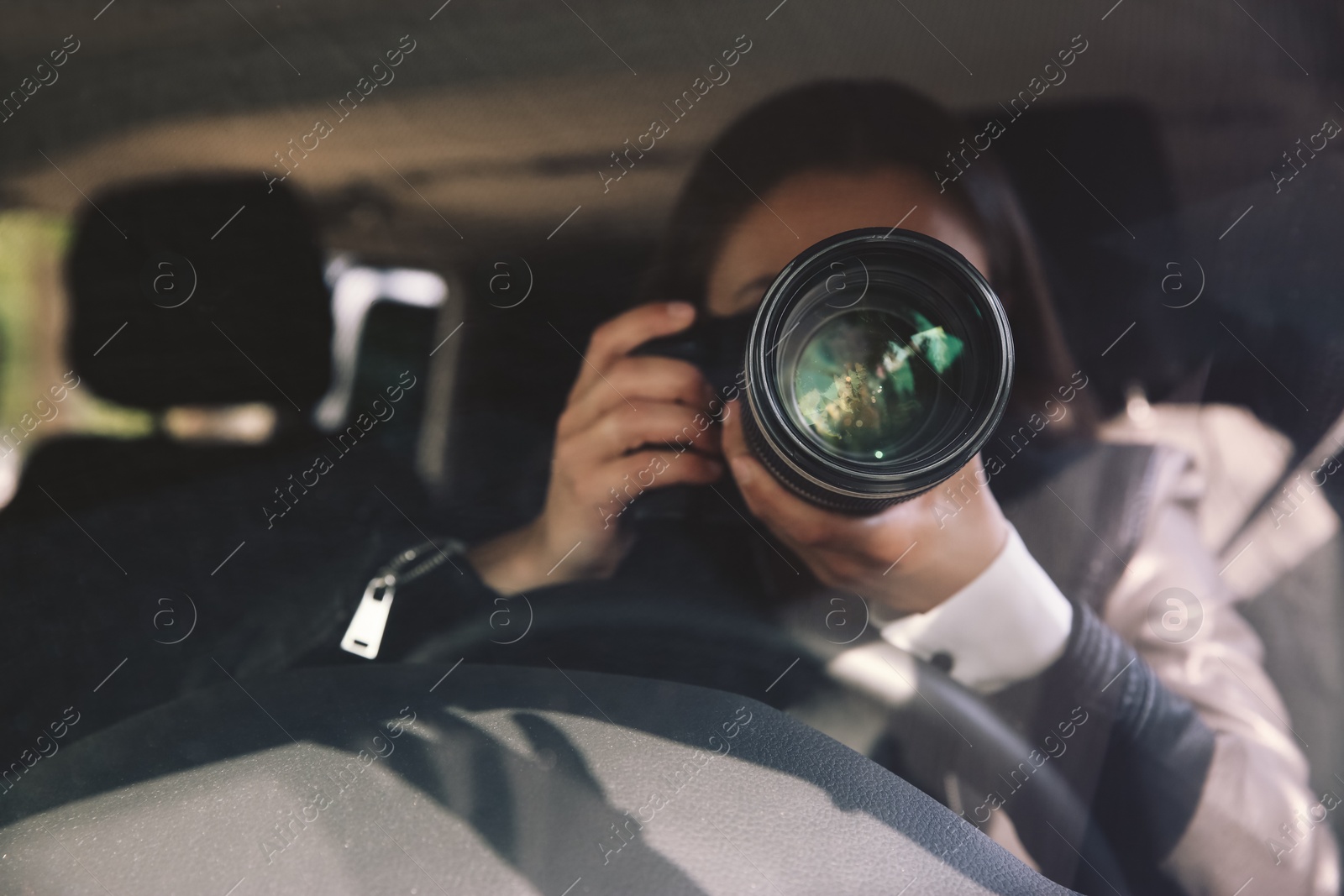 Photo of Private detective with camera spying from car