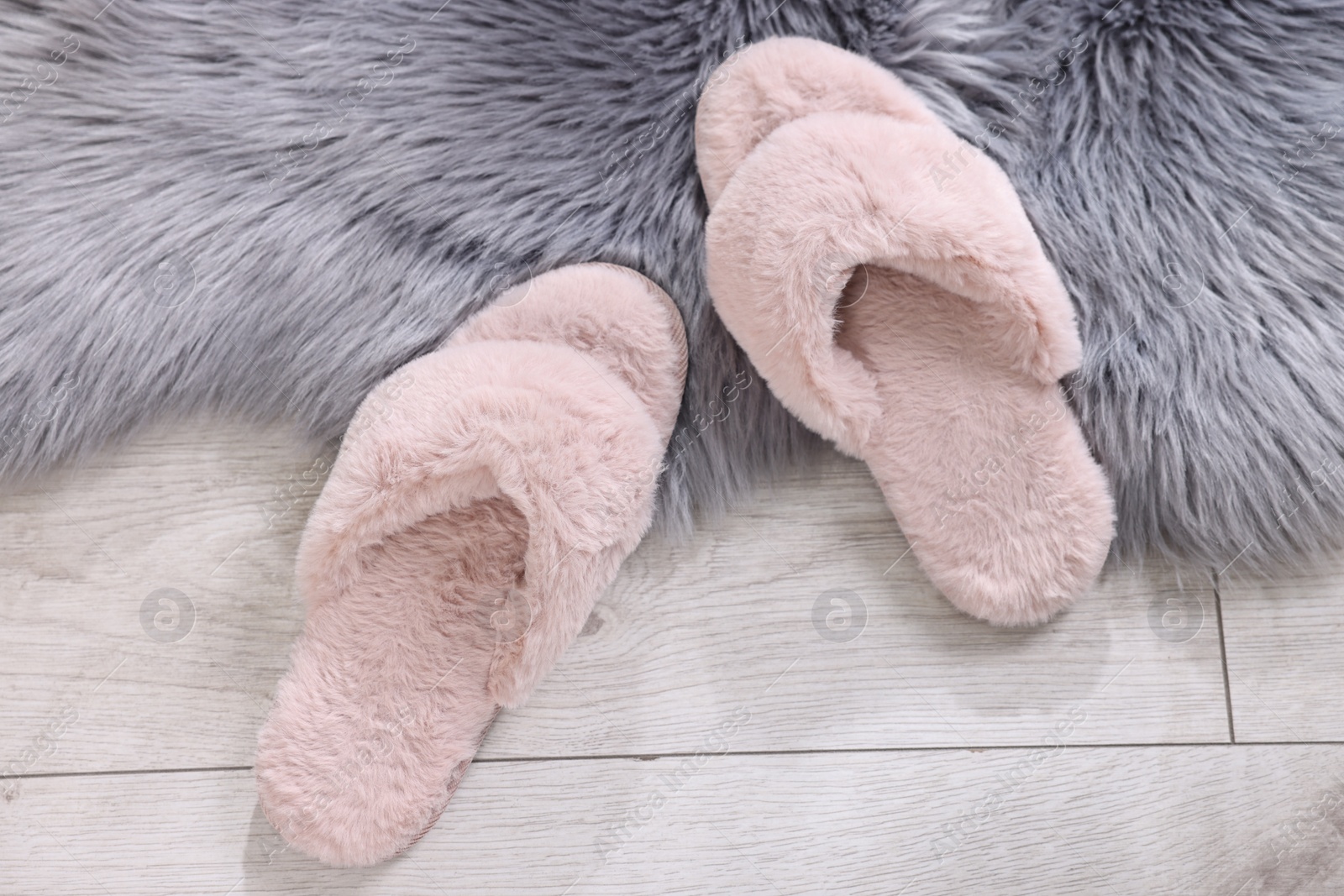 Photo of Pink soft slippers on light wooden floor at home, top view