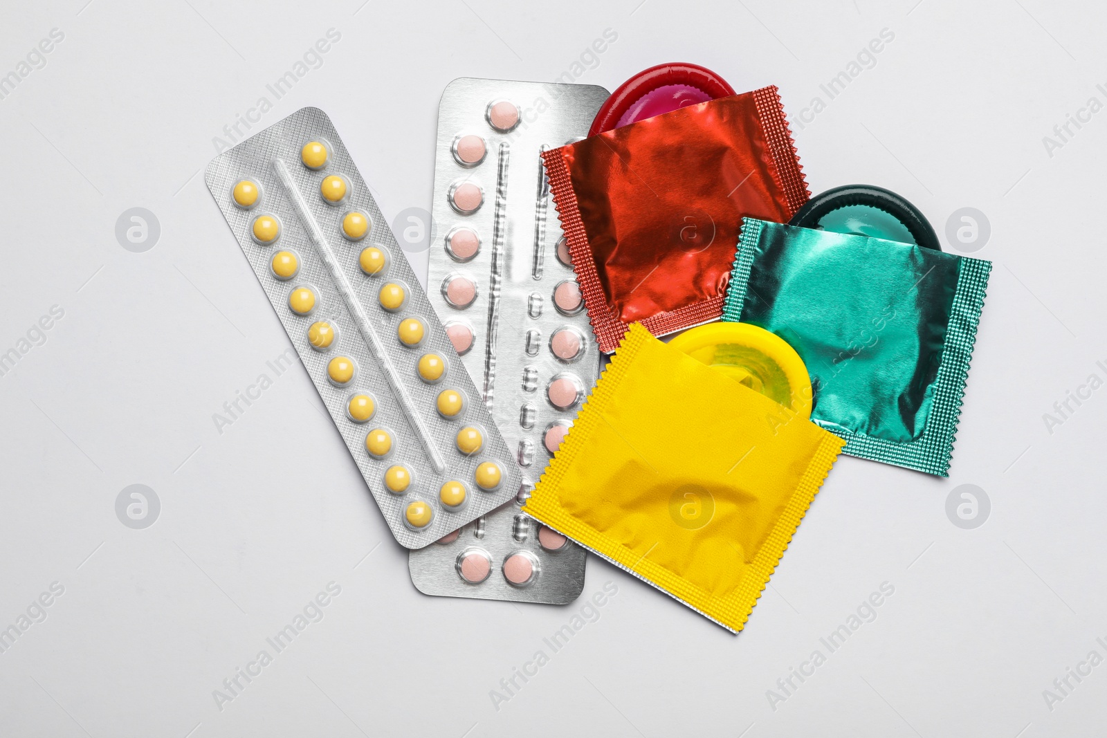 Photo of Condoms and birth control pills on white background, top view. Safe sex concept