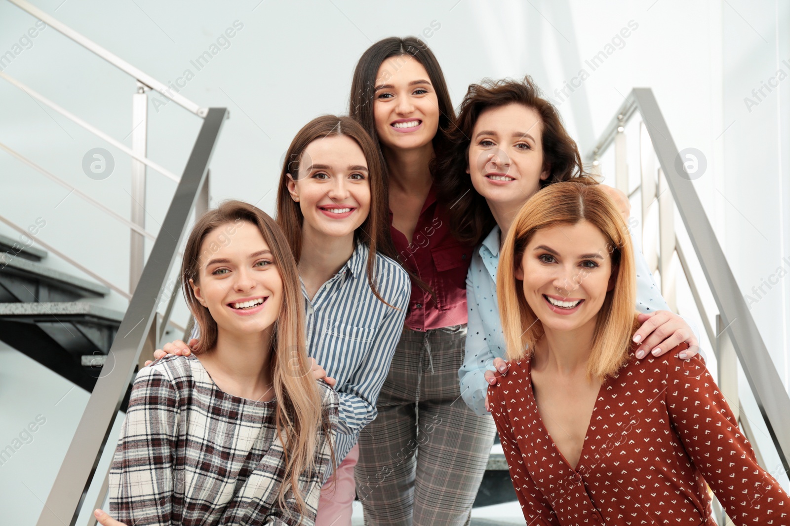 Photo of Portrait of happy ladies on stairs indoors. Women power concept