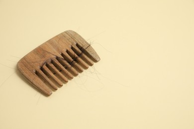 Photo of Wooden comb with lost hair on beige background. Space for text