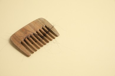 Wooden comb with lost hair on beige background. Space for text