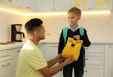 Father helping his little child get ready for school in kitchen