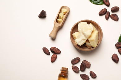 Photo of Organic cocoa butter, beans and essential oil on beige background, flat lay