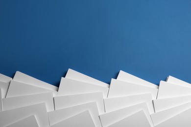 Photo of Many stacks of paper sheets on blue background, flat lay. Space for text