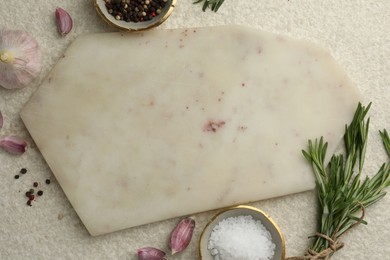 Photo of Cutting board, salt, pepper, rosemary and garlic on white textured table, flat lay. Space for text