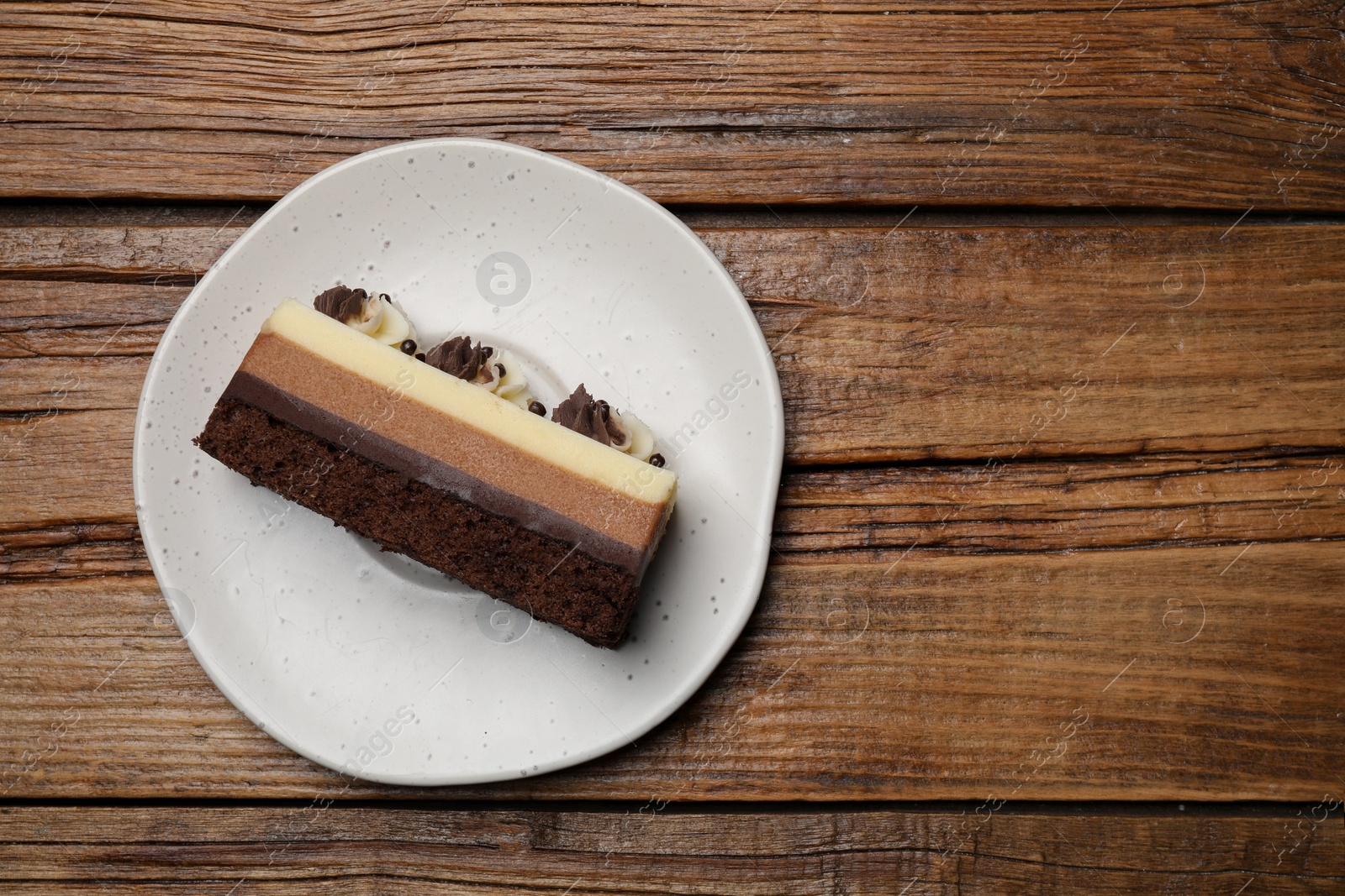 Photo of Plate with tasty chocolate mousse cake on wooden table, top view. Space for text