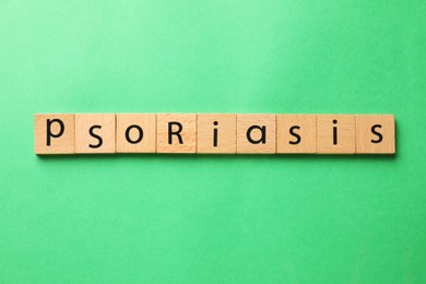 Word Psoriasis made of wooden squares with letters on green background, top view