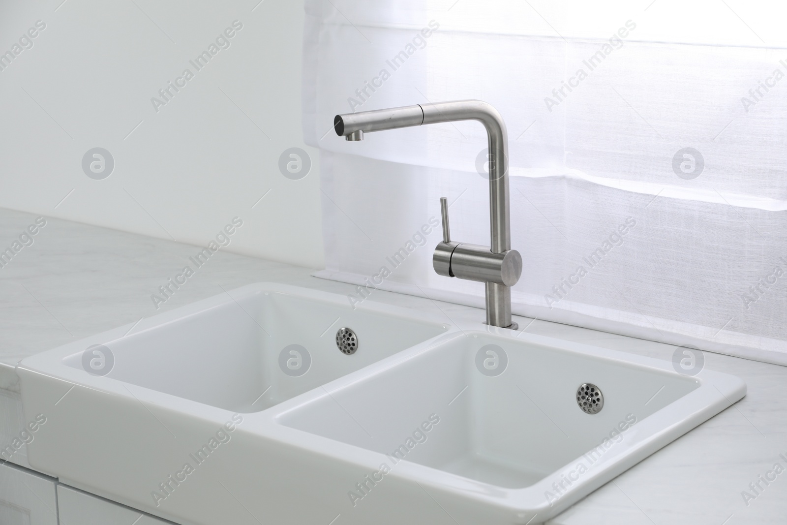 Photo of Modern sink and water tap near window in kitchen. Interior design