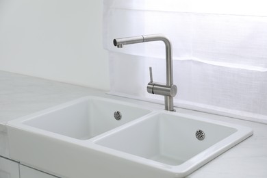 Modern sink and water tap near window in kitchen. Interior design