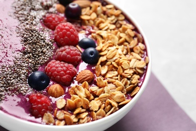 Delicious acai smoothie with granola and berries in bowl on table, closeup