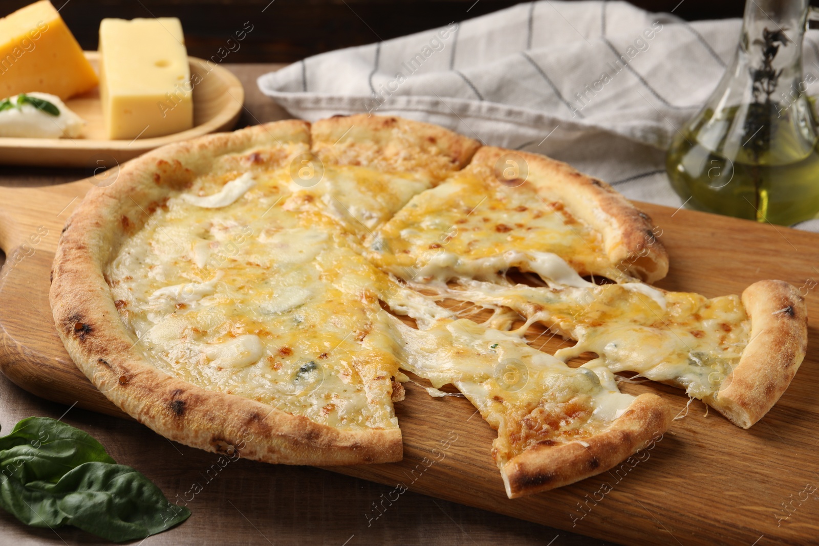 Photo of Delicious cut cheese pizza and ingredients on wooden table