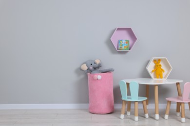 Photo of Kindergarten interior. Stylish furniture and toys near grey wall, space for text