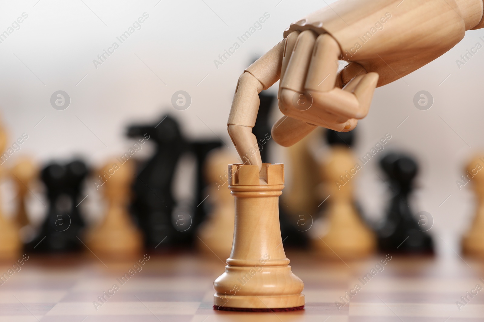 Photo of Robot moving chess piece on board against light background, closeup. Wooden hand representing artificial intelligence